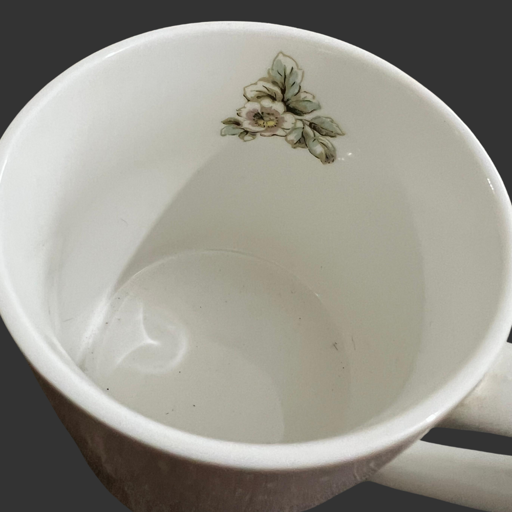 White ceramic mug with floral design on a dark background
