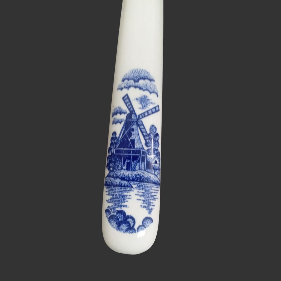 White ceramic spoon with blue windmill design on a black background