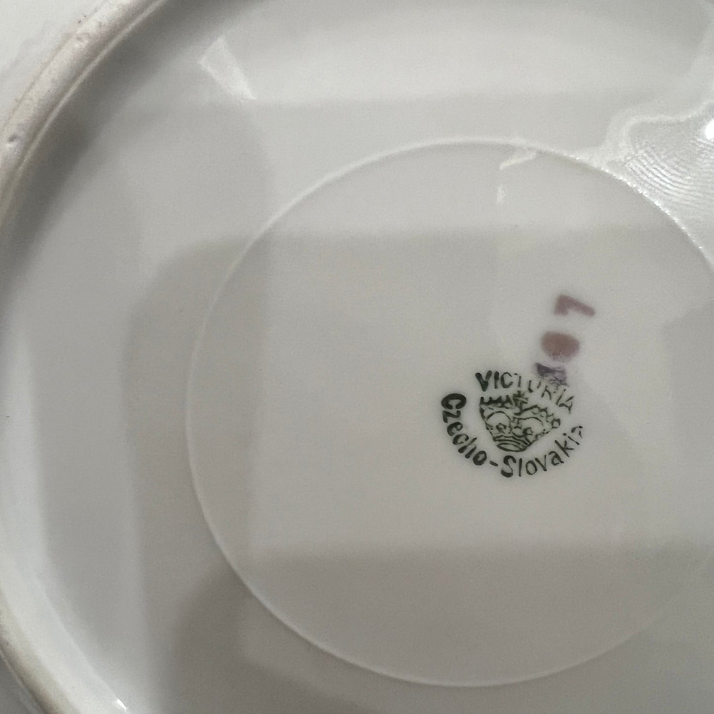 Close-up of a white ceramic plate with a visible brand logo on a white background