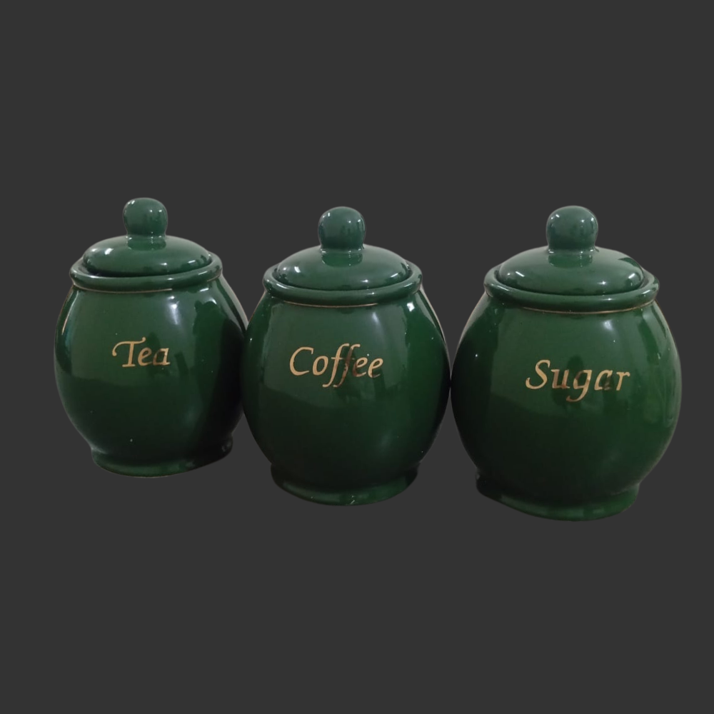 Set of three green ceramic canisters labeled 'Tea', 'Coffee', and 'Sugar' on a dark background.