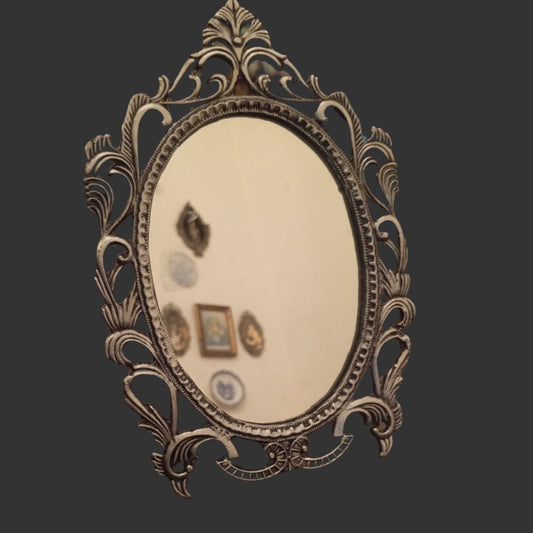 Decorative oval mirror with intricate gold frame on a dark background