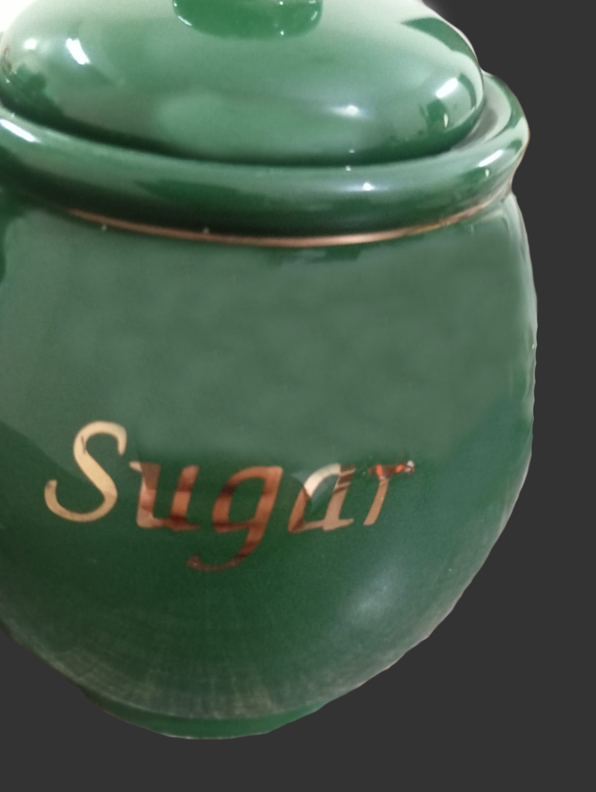 Green ceramic sugar jar with 'Sugar' inscription on a dark background